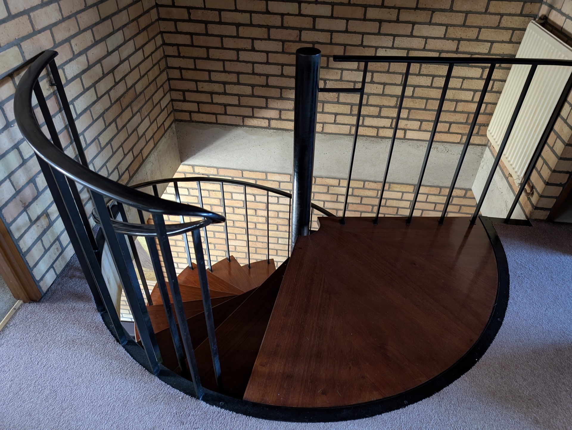Detail van de houten traptreden, zwarte balustrade en bakstenen wand